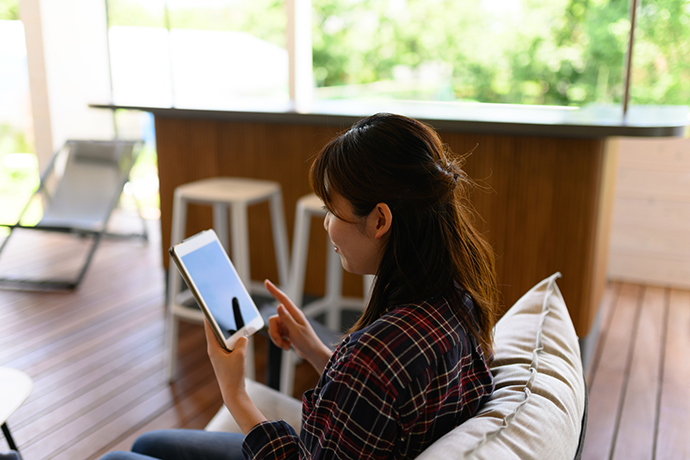 バルコニーでタブレットを見る女性